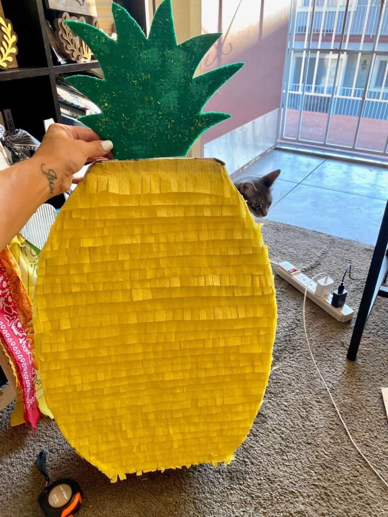 Fully decorated pineapple pinata with yellow crepe paper and a green glitter pineapple crown.