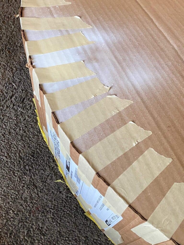 Begin to shape the long, bendy cardboard piece around the outline of the Pineapple, securing with masking tape every 1-2 inches. 