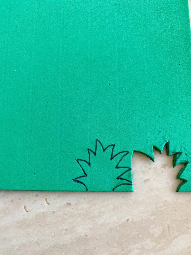 Draw the mini pineapple crowns onto the green glitter paper and cut them out.