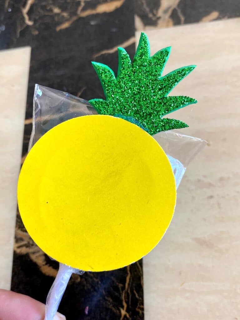 Glue the yellow circles and the green pineapple crowns to the lollipops
