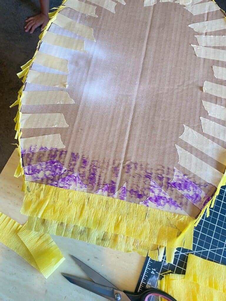 Glue the strips of yellow crepe paper across the front of the Pineapple, starting from the bottom and working your way up, overlapping them just a bit.