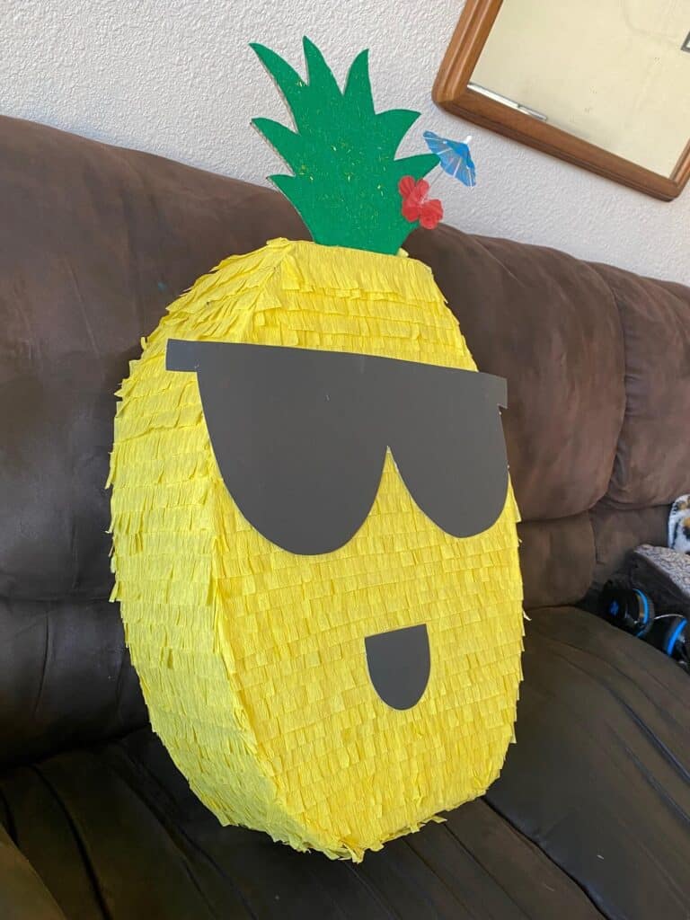 How to make a DIY Pineapple Piñata for a Hawaiian Luau or Pineapple themed birthday party, with cool dude sunglasses, a flower, and umbrella pic.