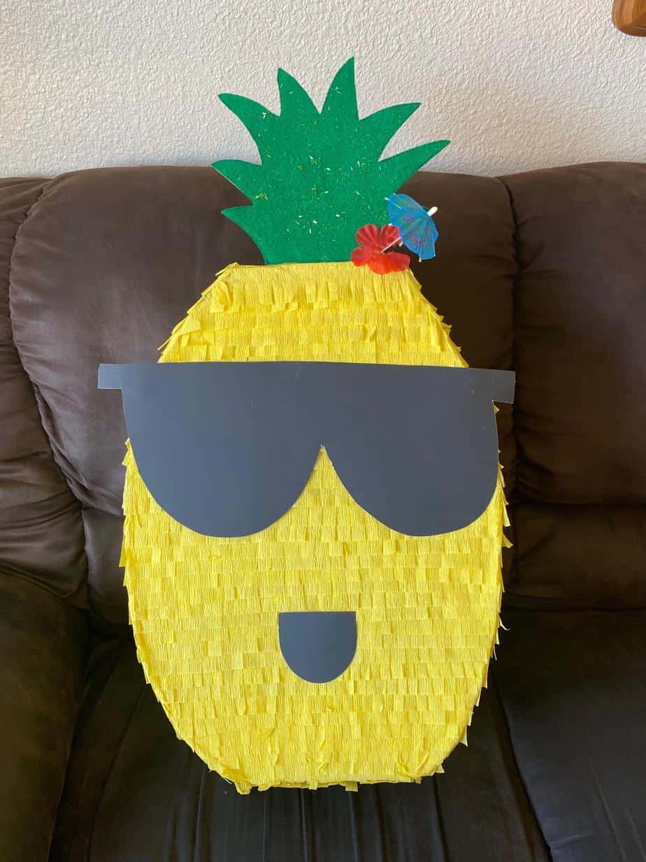 How to make a DIY Pineapple Piñata for a Hawaiian Luau or Pineapple themed birthday party, with cool dude sunglasses, a flower, and umbrella pic.