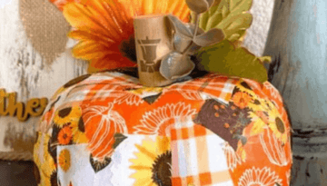 Dollar Tree Patchwork Foam Pumpkin covered with patches of Sunflower, orange, brown, and fall print fabric with a wine cork stem and sunflowers and greenery on top.