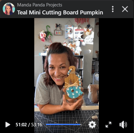 Amanda on a Facebook live holding the completed cutting board pumpkin project.