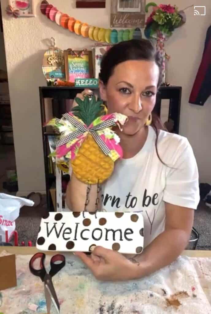 Amanda holding the completed thrift store pineapple welcome sign flip.