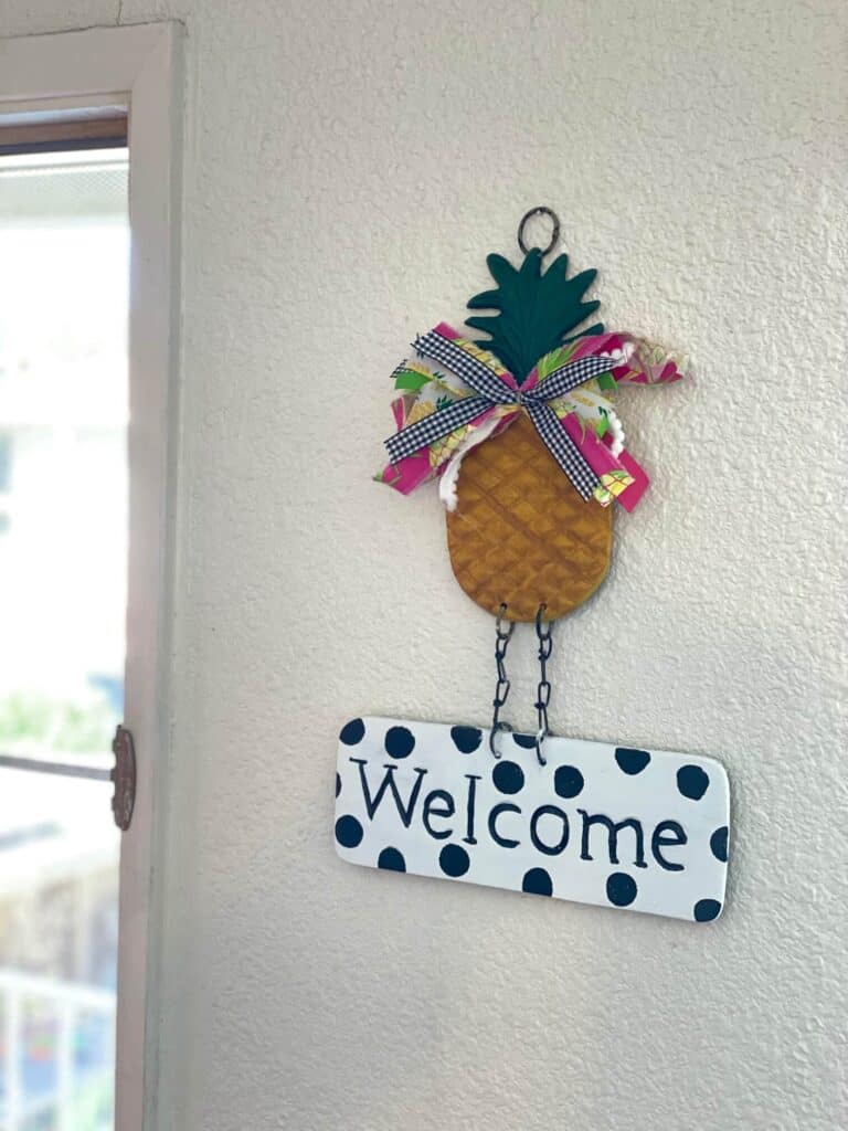 Thrift store Metal pineapple welcome sign hanging on the wall by the door.