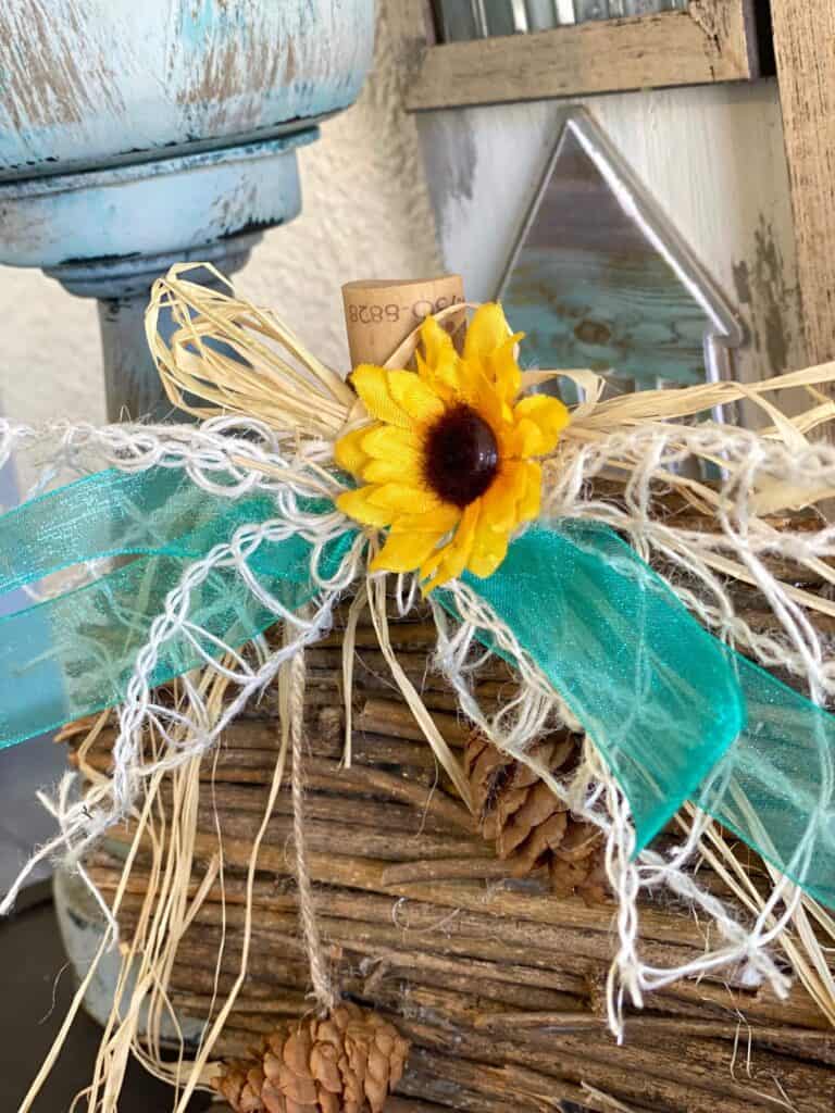 Close up of the sunflower, lattice, and teal bow on the wooden stick pumpkin.