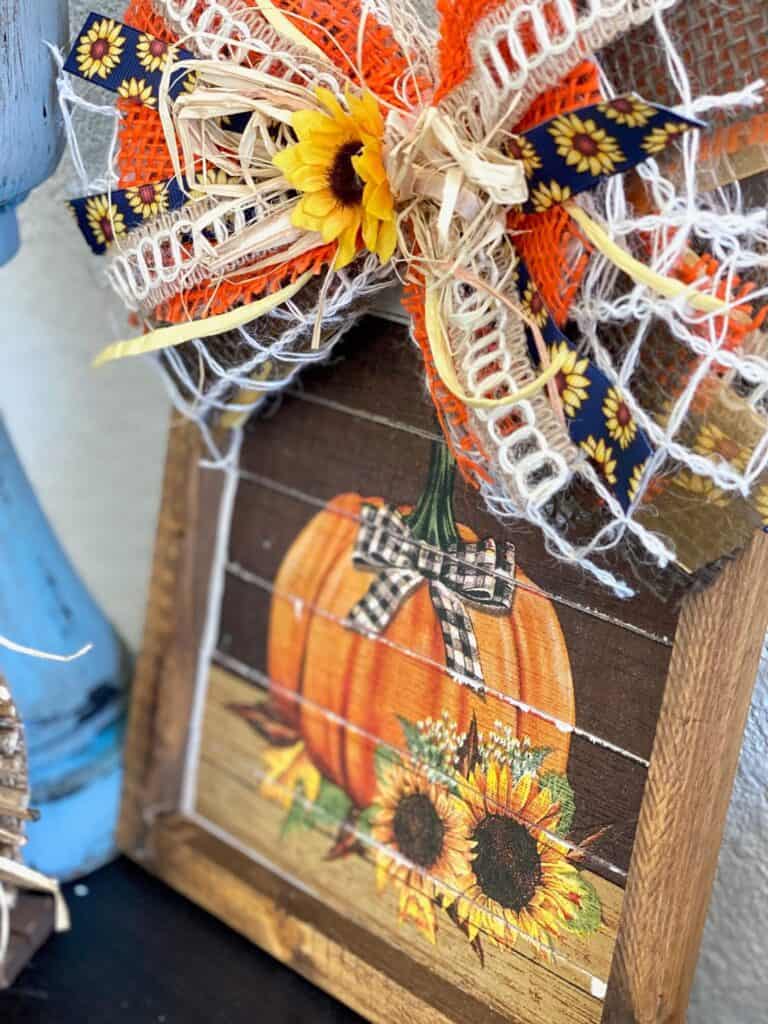 Side view of DIY Sunflower Pumpkin napkin reverse canvas fall craft decor with a big messy bow with autumn colors and vibe