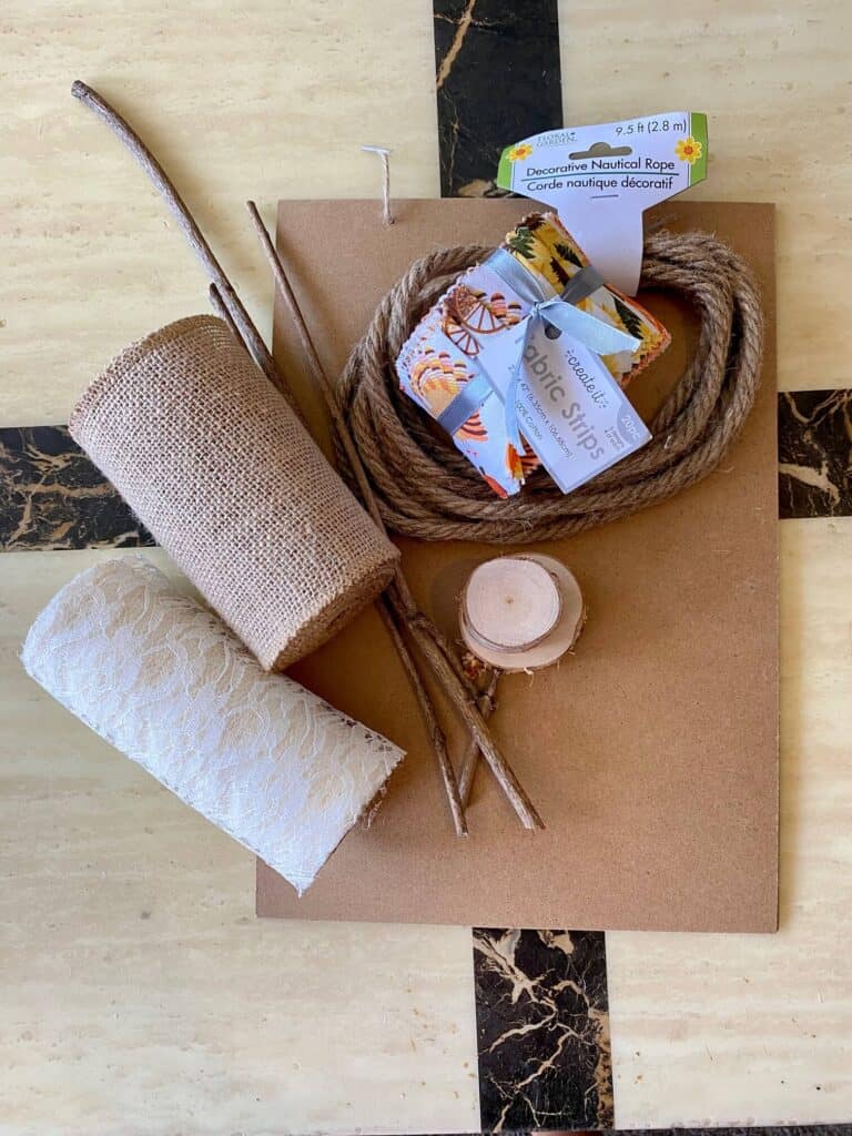 Supplies needed to make a fabric and burlap fall sunflower with sticks, a wooden board, rope, wooden rounds.