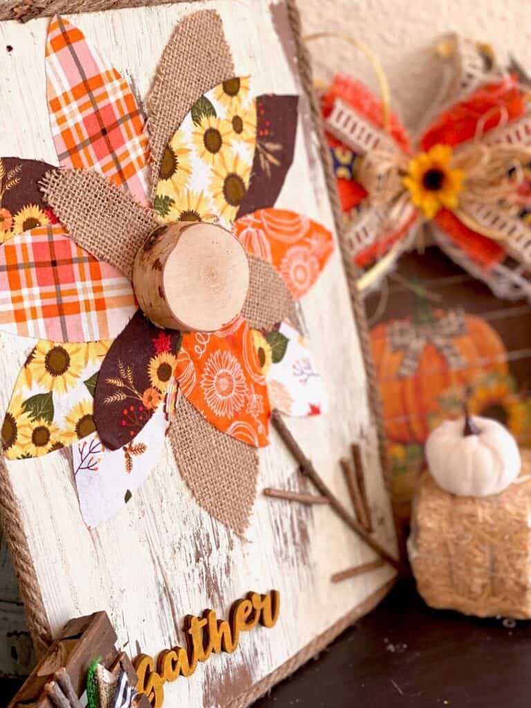 Close up side view of the Fall fabric and burlap sunflower diy decor with a little white pumpkin and hay bale behind.