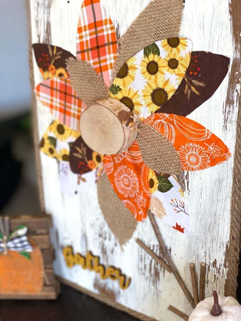 DIY Fall fabric and burlap sunflower with chippy paint background and jute rope rim and a wooden cutout of the word "gather". Autumn decor.