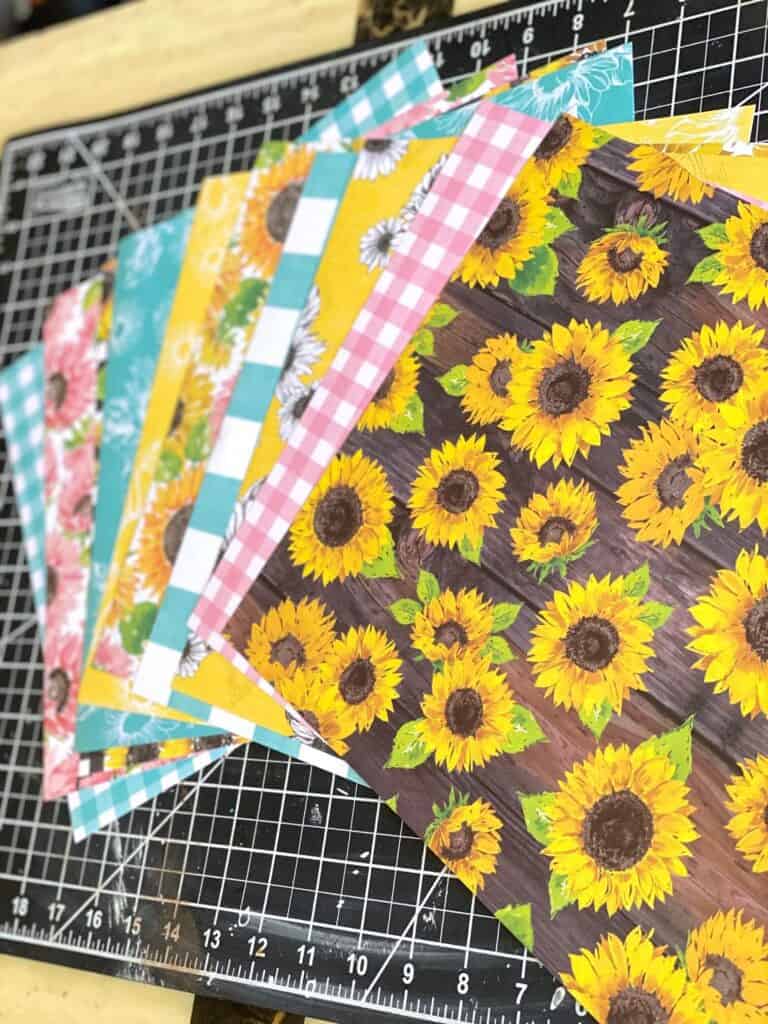 10 pieces of Sunflower themed scrapbook paper fanned out.