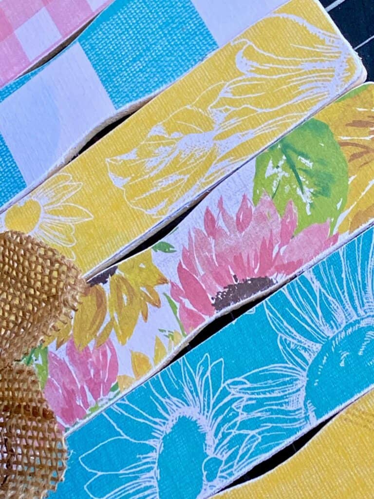 Close up of the pink, yellow, and teal sunflower scrapbook paper mod podged to the paint sticks.