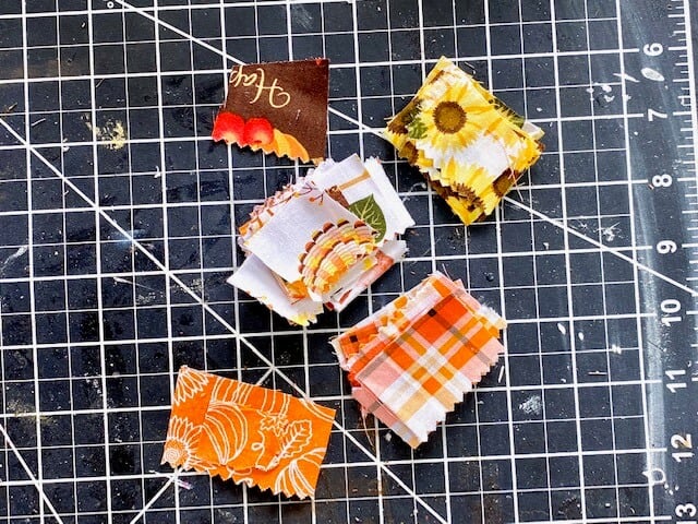 Swatches of different fall print fabrics cut into 2x2 squares with pinking sheered edges.