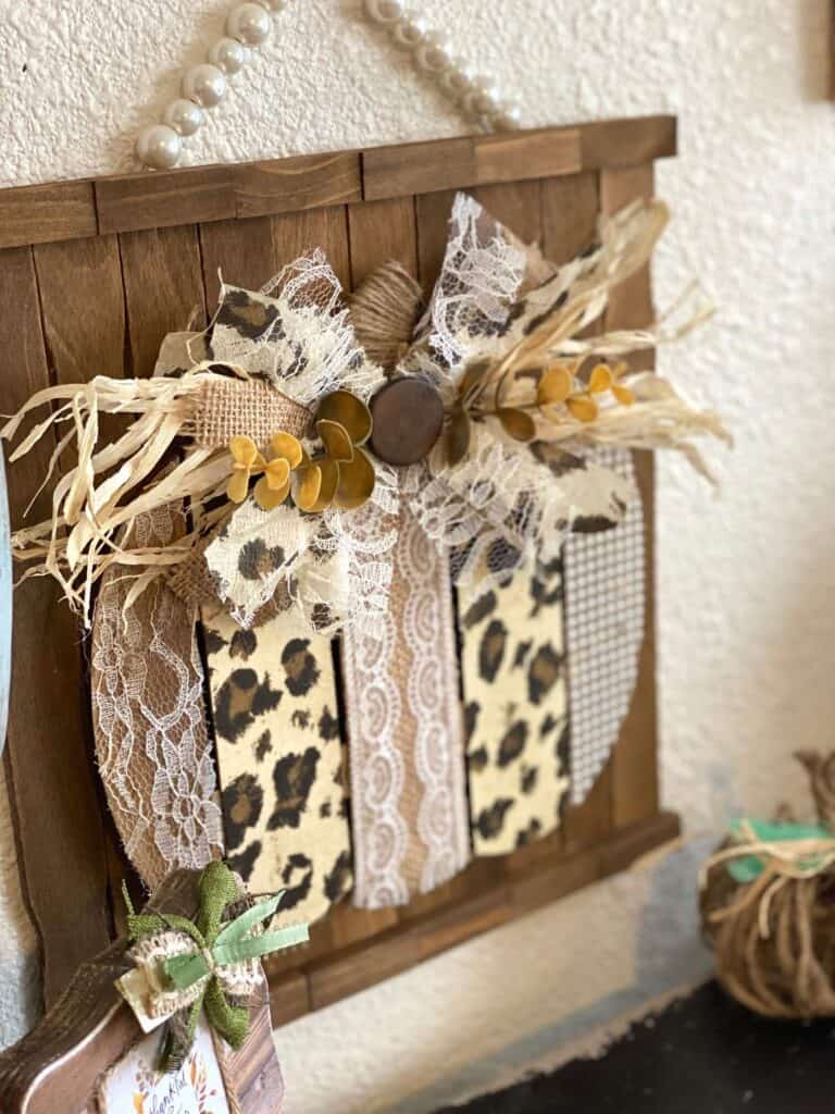Dollar Tree Leopard Print pumpkin fall DIY crafts and decor with lace, burlap, pearl made on a background of stained paint sticks and jenga blocks with a messy bow.