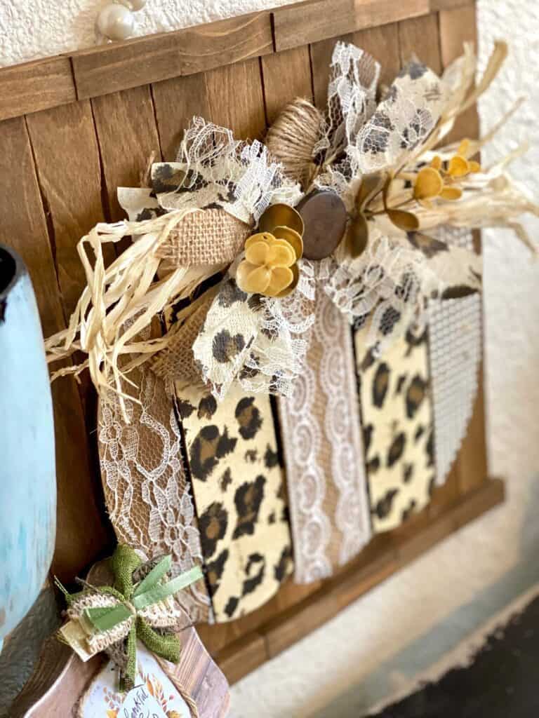 Dollar Tree Leopard Print pumpkin fall DIY crafts and decor with lace, burlap, pearl made on a background of stained paint sticks and jenga blocks with a messy bow.