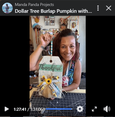 Amanda holding the competed burlap pumpkin door hanger on a Facebook Live.