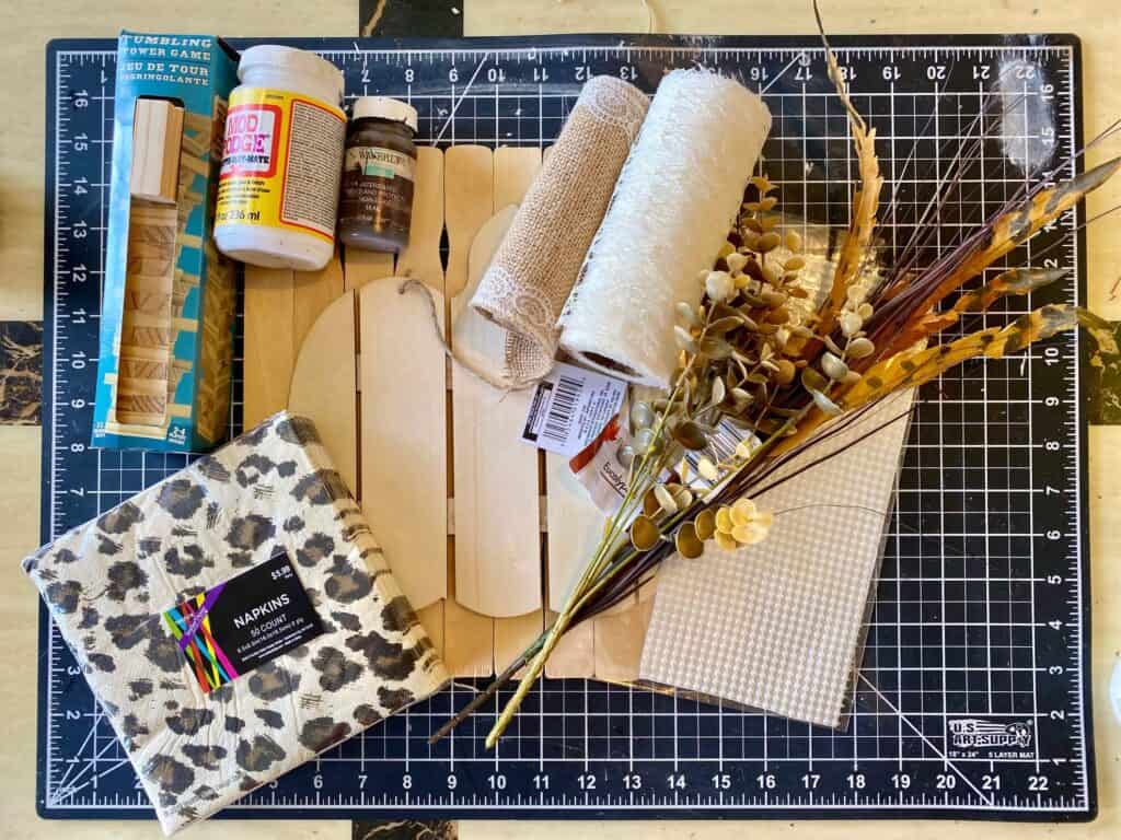 Supplies needed to make a Dollar Tree Leopard Print Pumpkin with napkins, lace, burlap, pearls and a wooden slated pumpkin on a paint stick and jenga block frame.