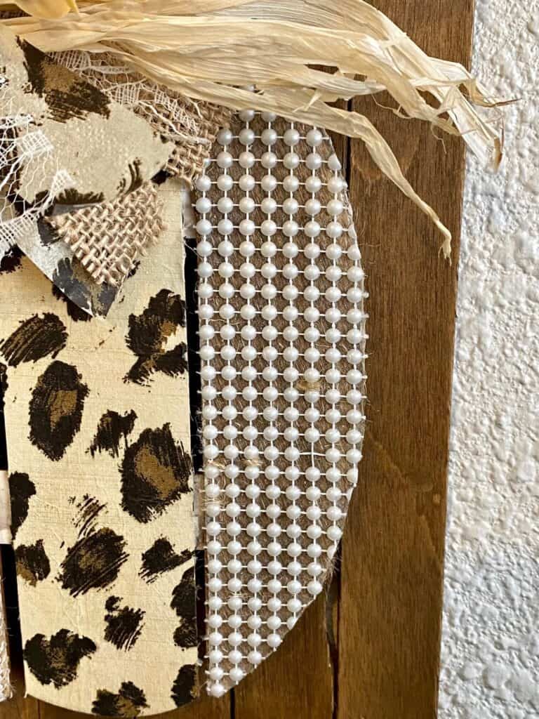 Close up of the pearl bead adhesive strip and the leopard print napkin on the wooden pumpkin.