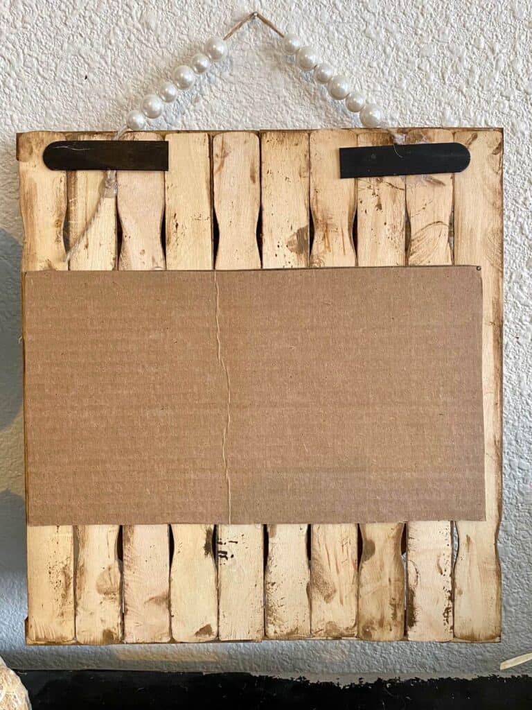 The back of the project showing the paint sticks glued to a piece of cardboard backing.