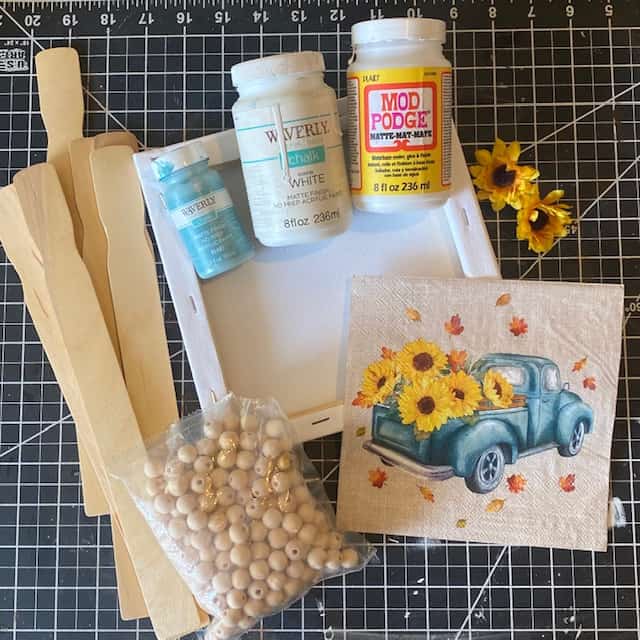Supplies needed to make a Sunflower Truck Napkin reverse canvas with paint sticks, and a wood bead hanger.