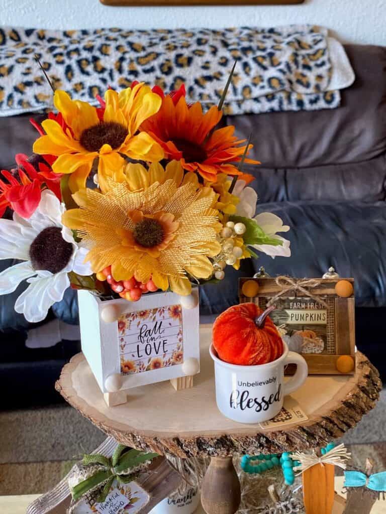 Top tier of the wooden tray with a mixed sunflower bouquet, mini mug that says "unbelievably blessed" with a pumpkin inside, and a mini wooden pumpkin frame.