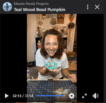Amanda holding the completed wood bead pumpkin project on her Facebook live.