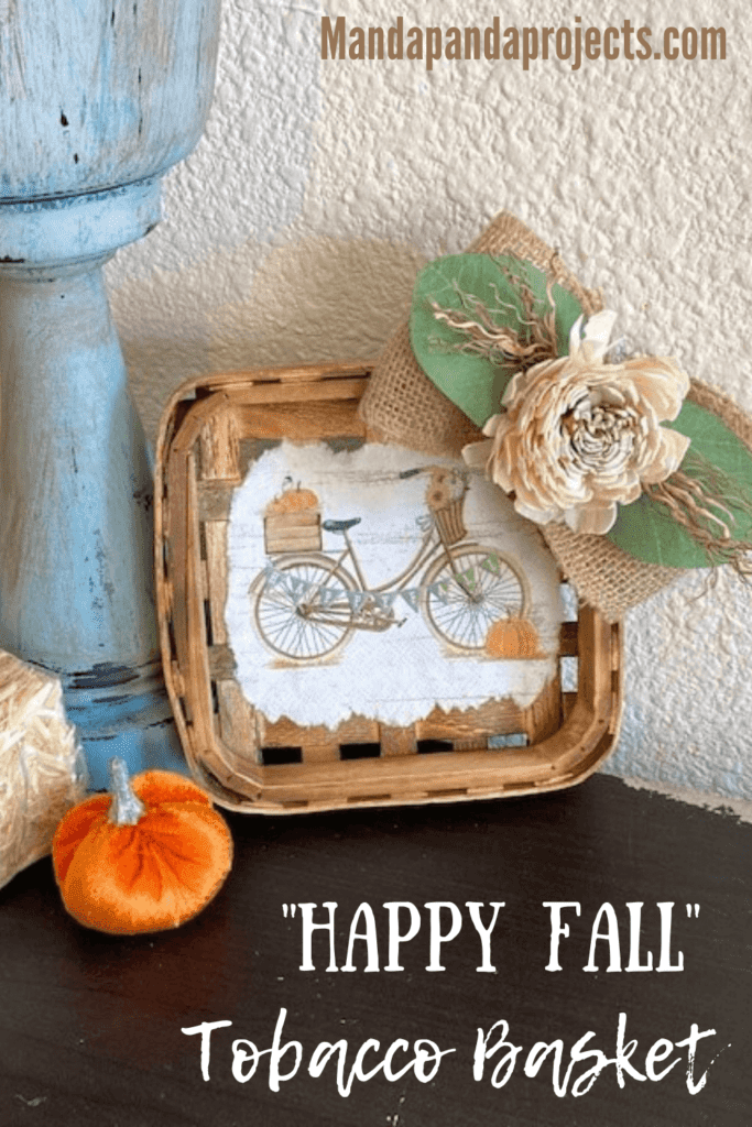 Fall Vintage Bicycle Tobacco Basket made with a cocktail napkin mod podged to the center of a small burlap bow with wood flower and lambs ear, hanging on a white wall.