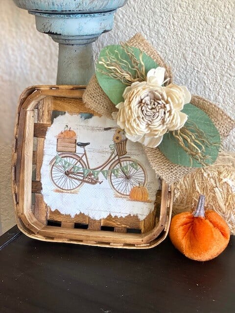 Fall Vintage Bicycle Tobacco Basket next to a candlestick on a bookcase with a velvet pumpkin.