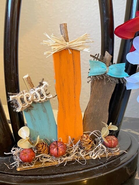 Paint stick pumpkin patch made with recycled ends of paint sticks for a DIY mini piece of fall decor for your tiered tray with Teal, orange and brown pumpkins and mini pinecones with spanish moss.