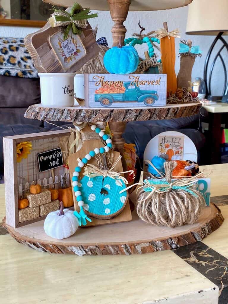 Bottom tier of the tray with the mini 10 cent pumpkin patch, teal cutting board pumpkin, twine pumpkin, and "Hello Autumn" crate.