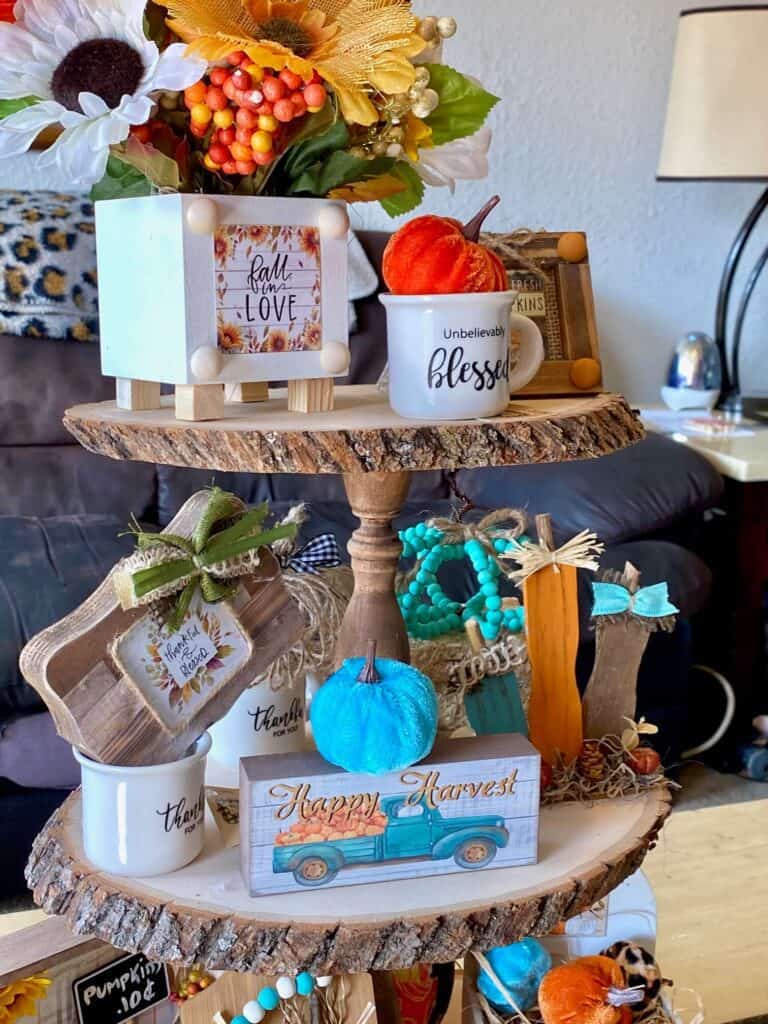 Middle tier of the tray with a "Happy Harvest" truck, mini pumpkin patch, mini mug that says "thankful for you" and a dollar tree block that says "thankful and blessed".
