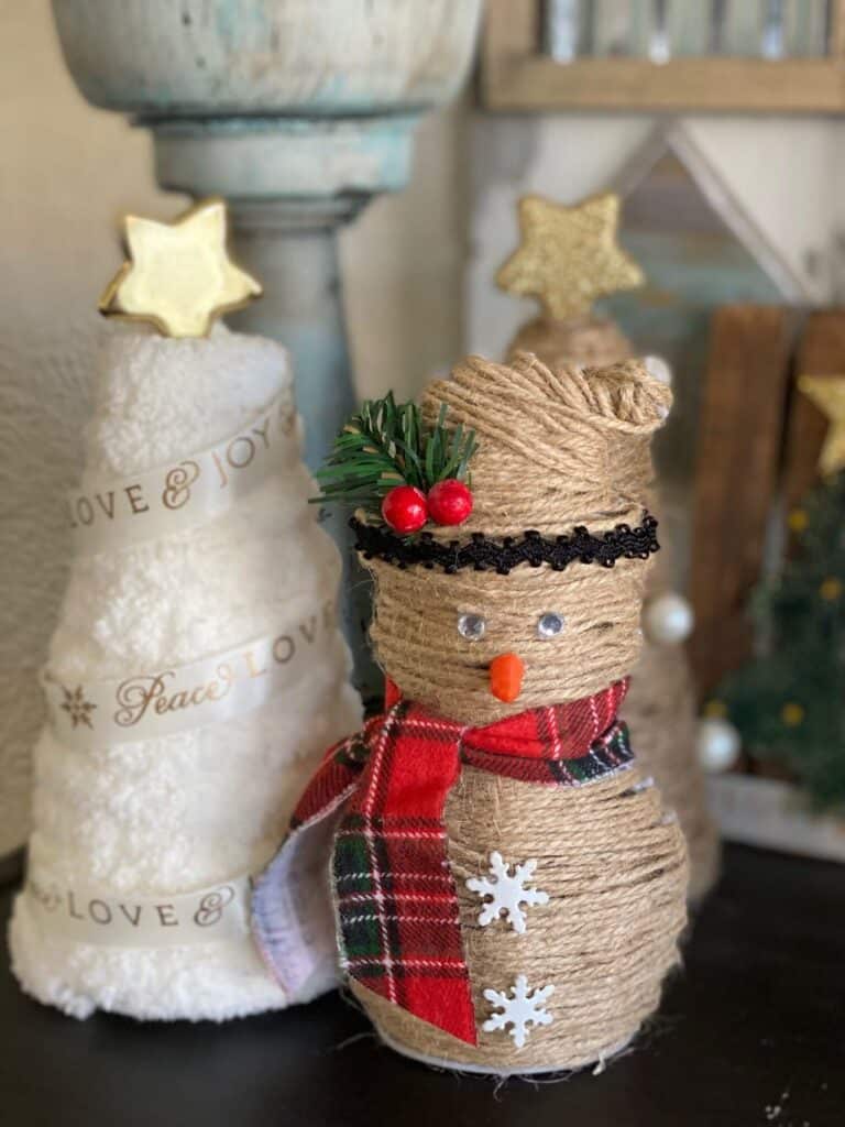 Rustic twine snowman in front of the rustic twine and white yarn wrapped foam cone trees.