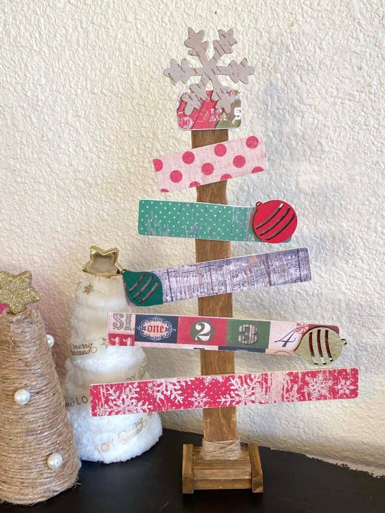 Paint stick Christmas tree with vintage scrapbook paper and wooden ornament embellishments. Handmade vintage Christmas decorations next to twine foam cone trees.