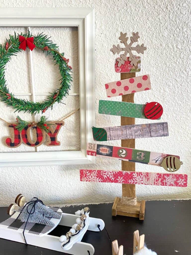Paint stick christmas tree with vintage scrapbook paper next to a christmas wreath window frame.