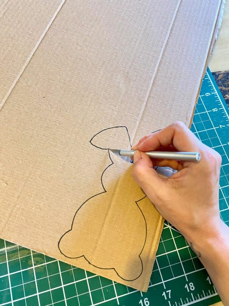 Cutting out the cardboard easter bunny with an X-acto knife.