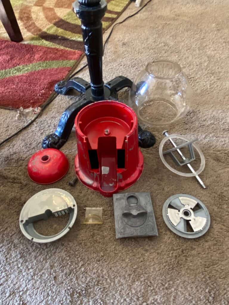 The vintage gumball machine completely taken apart and disassembled.  