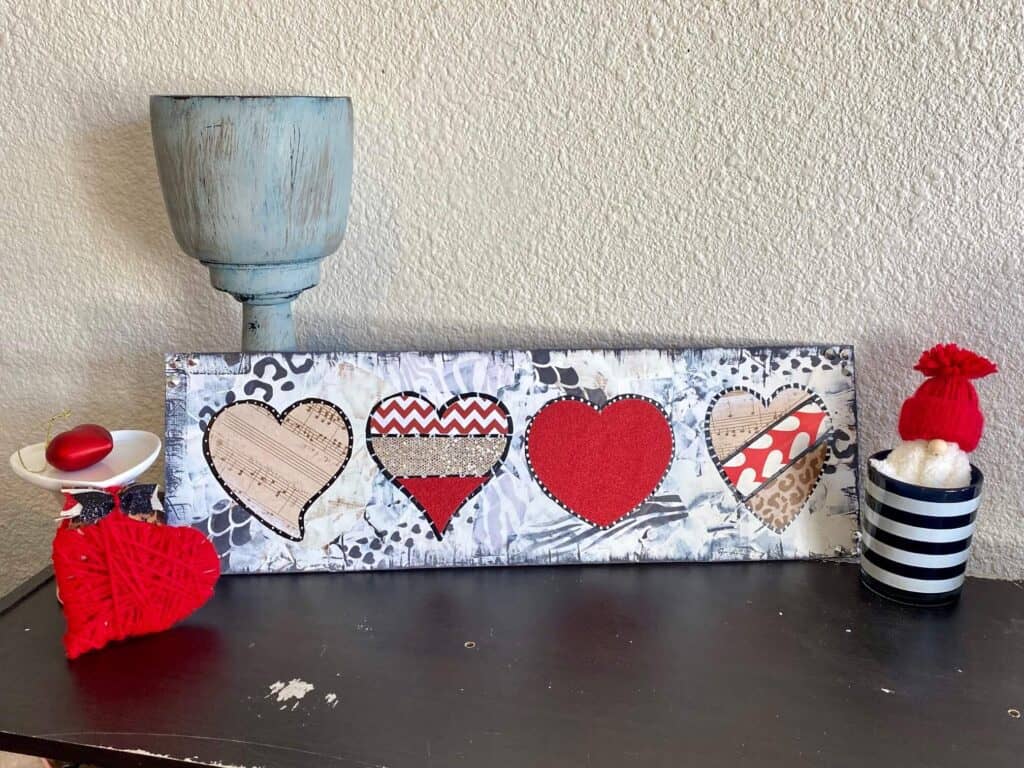 Mixed Media Funky Valentine's Day Hearts crafty decor idea for February 14th with red, leopard, and black and white background on a long wooden board.