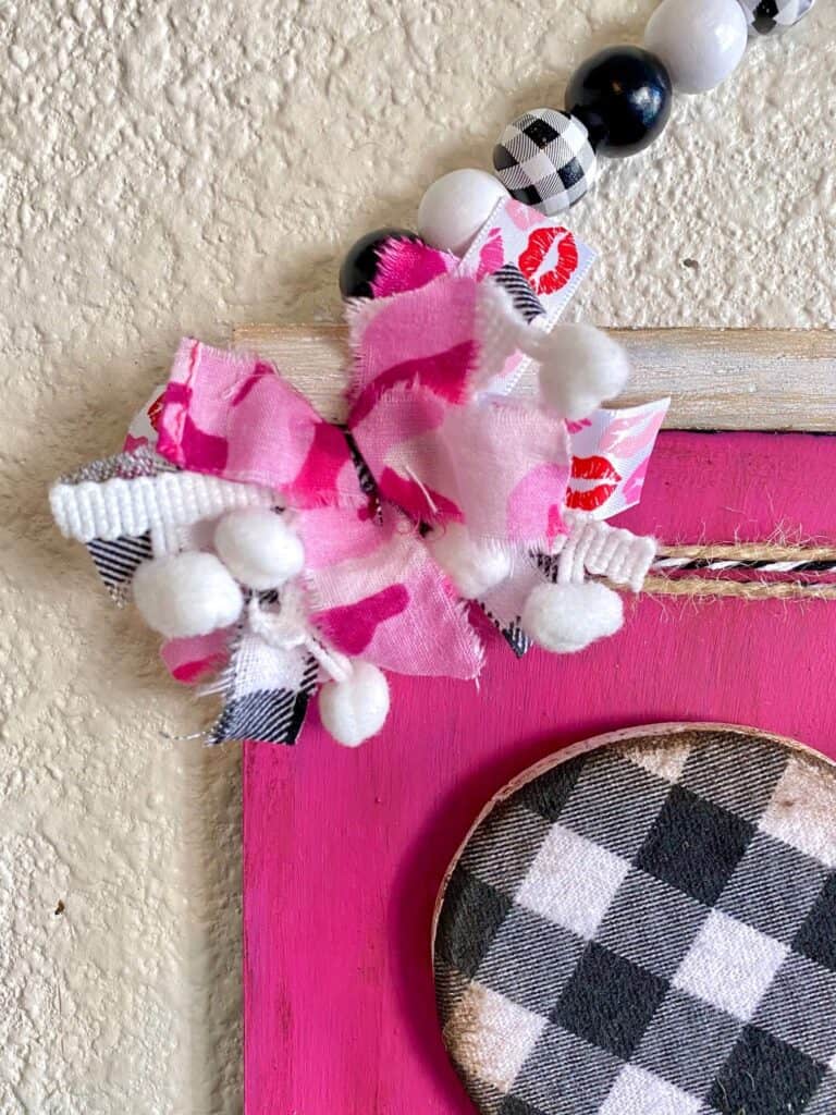 Small mini messy bow with pink, white, and buffalo check fabric fabric with pom poms.