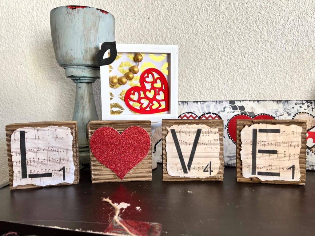 Love blocks with a red glitter heart for the "O" and corrugated cardboard with music sheet scrapbook paper with burnt edges on top.