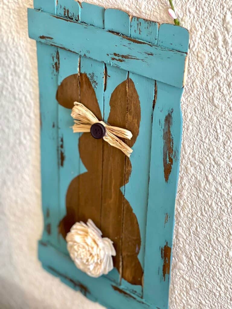 Close up of the wood easter bunny with a raffia button bow in its ears and chippy teal paint.