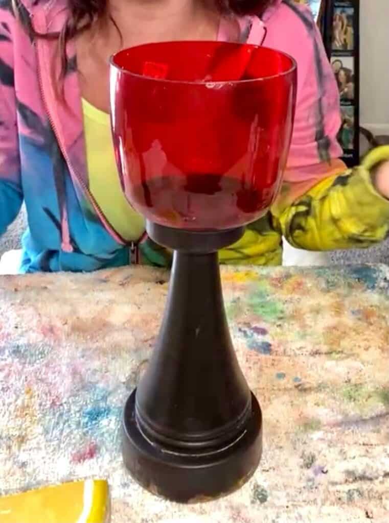 The thrift store chunky candlestick before it was made over and painted. The top is red glass and the bottom is black with rust along the bottom rim.