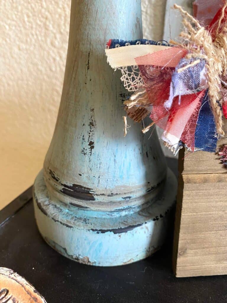 The bottom of the thrift store candlestick showing the black coming through underneath the agave chalk paint.