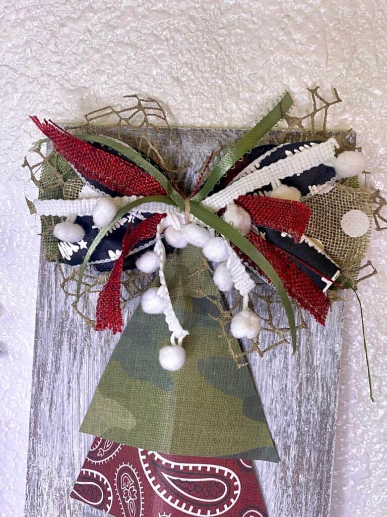 Messy bow at the top of the Christmas tree with coordinating ribbon and white pom pom trim.