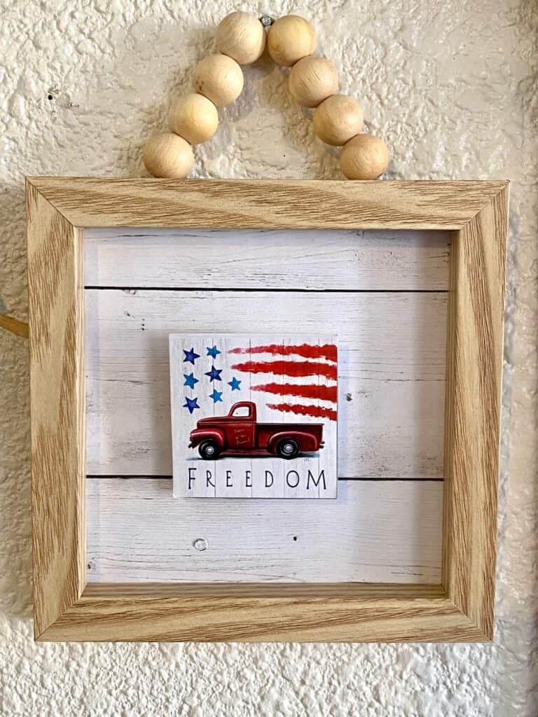 Small wooden frame with wood bead hanger and faux shiplap background and Dollar Tree back of the calendar mini "freedom" americana truck.