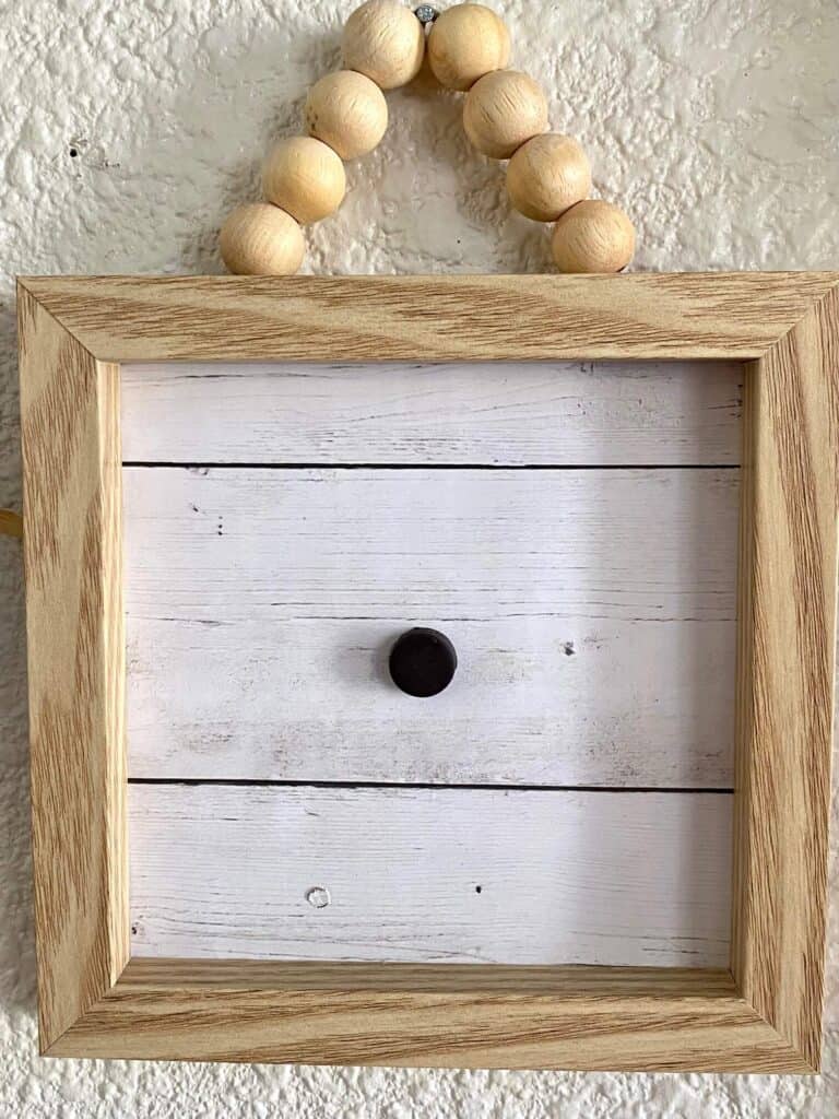 Small wooden frame with wood bead hanger and faux shiplap background and a magnet to make the frame interchangeable for all the seasons and holidays.