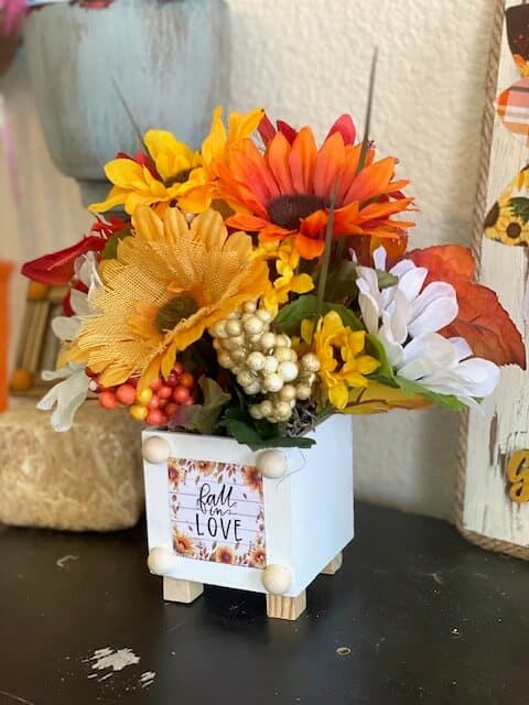 Side view of the Dollar Tree Mixed Sunflower bouquet with a "Fall in Love" Mini calendar print on the front.