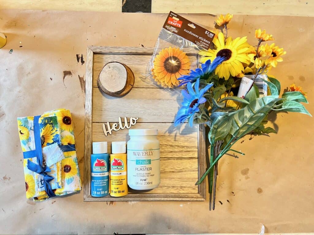 Supplies needed to make a DIY Blue and Yellow fabric sunflower craft with wooden round.