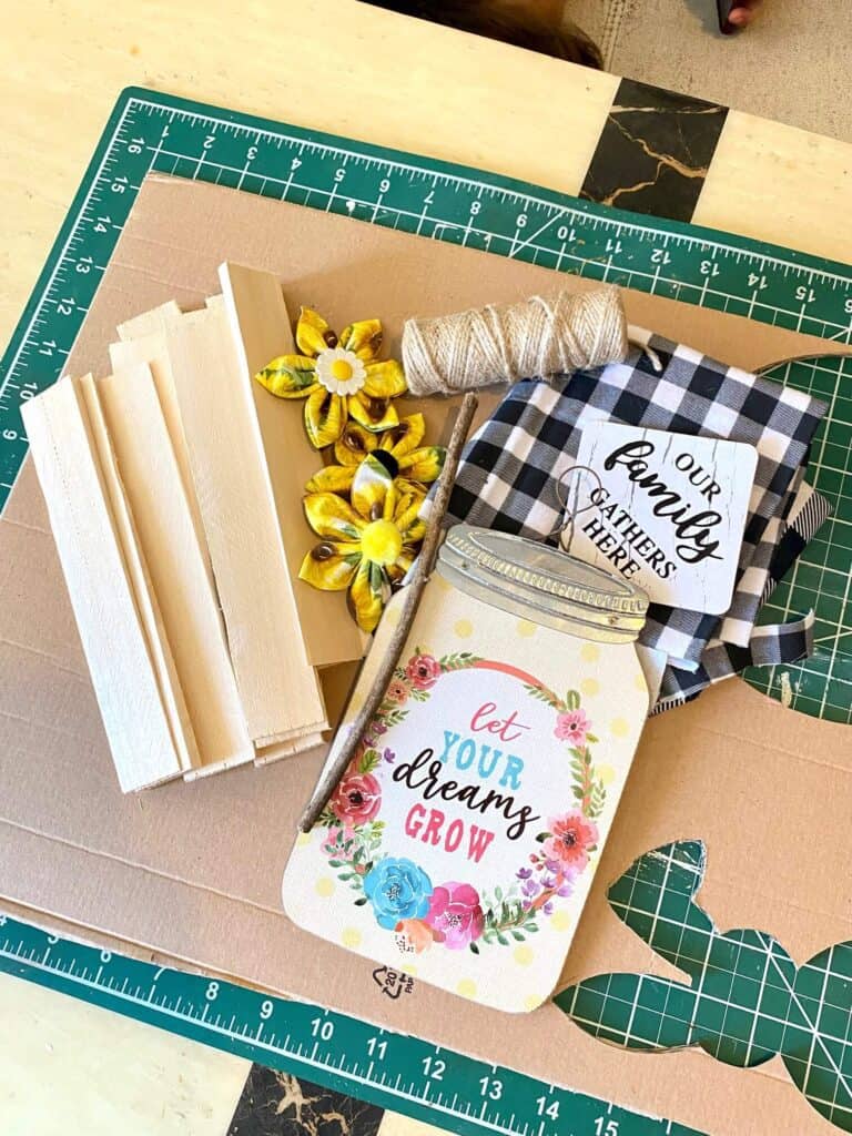 Supplies needed to make a DIY Mason Jar with sewn fabric flowers on a wooden shim background.